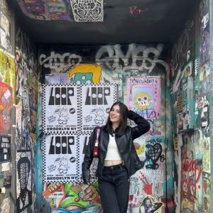 Milla Reichenberg posing in front of a graffiti covered wall.