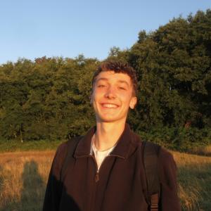 Nathan Kellison-Miller smiling in front of trees and a blue sky.