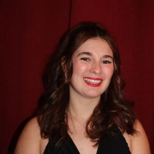 Sara Kurth smiling in front of a red background.