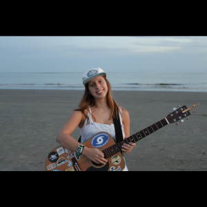 Susanna Woodward smiling while holding a guitar.