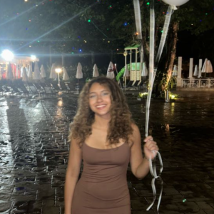 Thayna Henrique smiling while holding white balloons.