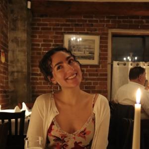 Noor Jawed smiling while sitting at a dining table.