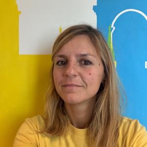 Rome Center Director, Simona, poses wearing a yellow shirt.