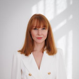 Woman with red hair in white holding a microphone