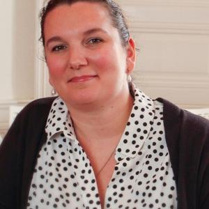 Woman smiling in black and white polka dot shirt with hair back in a ponytail 