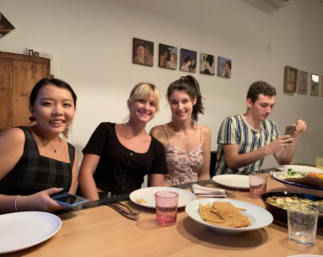 Students with their host mom seated around a dinner table at a homestay in Nice.