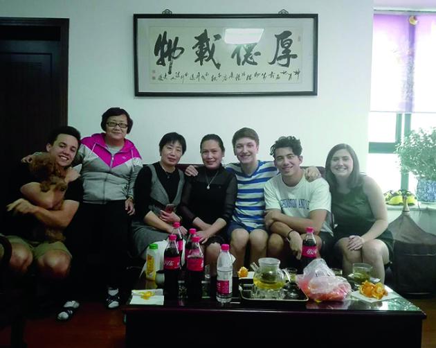 Students sit with their host family with a table full of dumplings and drinks in a Shanghai homestay.