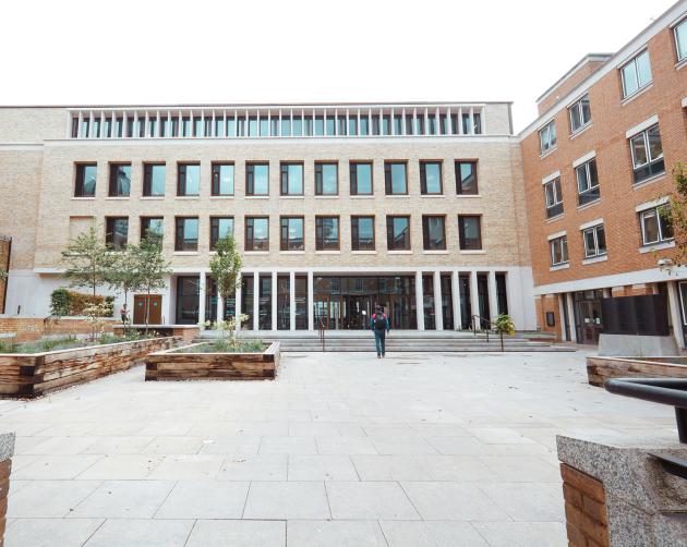 A student enters University College London, a brick building with multiple windows.
