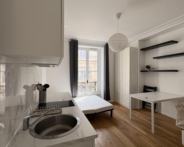 Room in Paris with bed, table, and small kitchen