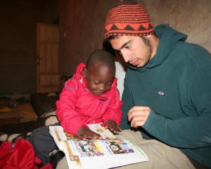 Child and adult reading a book together, seated indoors, focused and engaged. This alt text was added with Al; accuracy may vary.