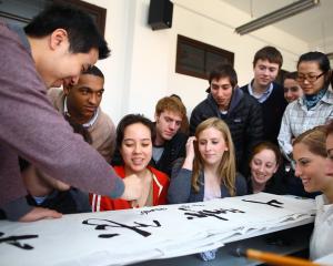 a diverse group of students looking at Chinese characters on a page