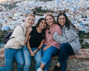 four students pose for a photo in Chefchaouen Morocco overlooking the city below