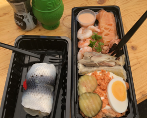a container wityh fish, eggs, cucumbers, shrimp