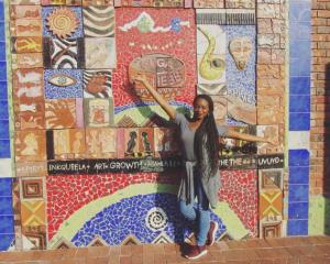 a girl standing near the wall with african art 