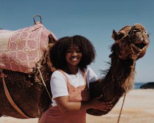 student smiling next to camel in the Sahara desert