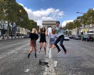 Students jumping and happy in front of the Arc de Triomphe in Paris