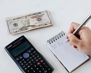 using a calculator and notepad to budget money