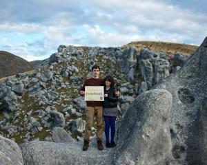 two students stand on limestones boulders in New Zealand.