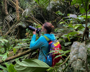 Student holding a camera in the jungle