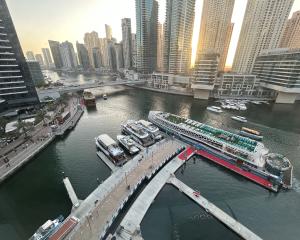 Aerial view of a marina in Dubai with skyscrapers and boats at sunset. 