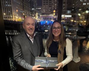 Man and woman standing next to each other with an award in front of night skyline