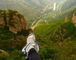 a picture of a girl's legs with shoes with a mountain background 