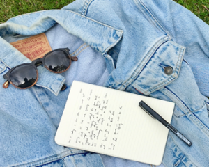 a picture of a blue jacket, a note, a pen and glasses laying on it 