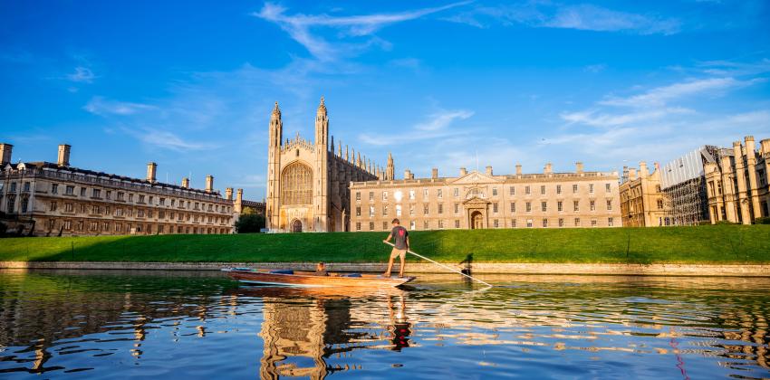 A landscape image of Kings College from across the Cam River. A group of people are punting down the river.