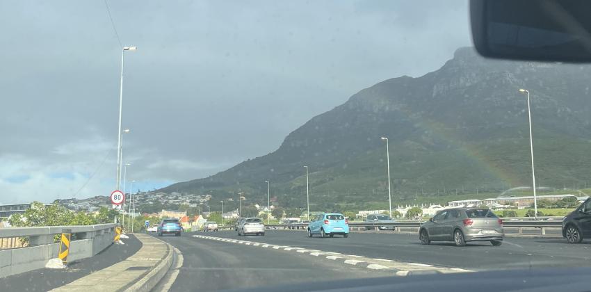 An image shows a road, mountains, and rainbow