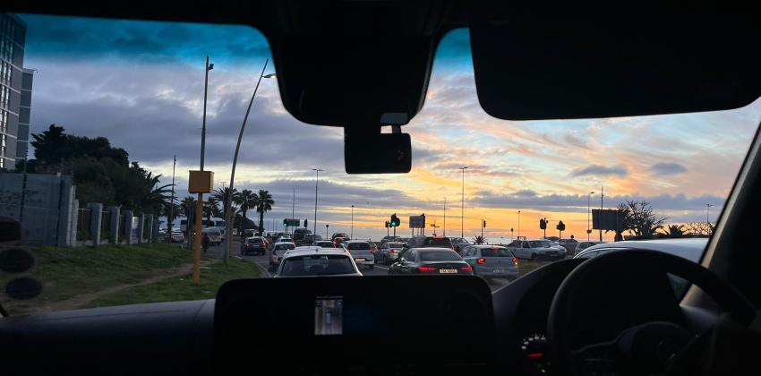 The image shows a view from the front window of the van showing sunset 