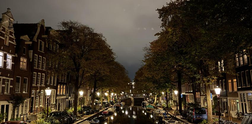 A river with trees and sidewalk to its sides at night