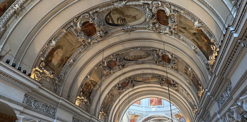 The ceiling in the Salzburg Cathedral. It is very ornate, with sepia-tone frescoes and lots of detailed architecture.