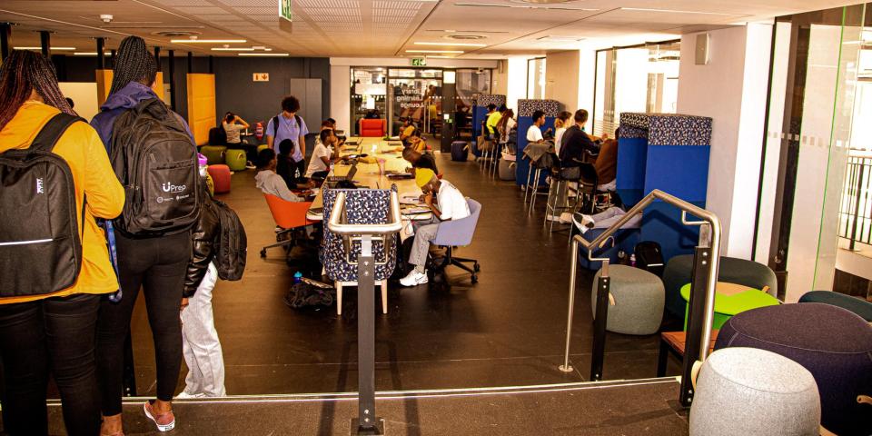Picture of the library learning lounge in the Chris Hani Building on the UCT upper campus. Picture depicts students studying and moving around in a modern study space. 