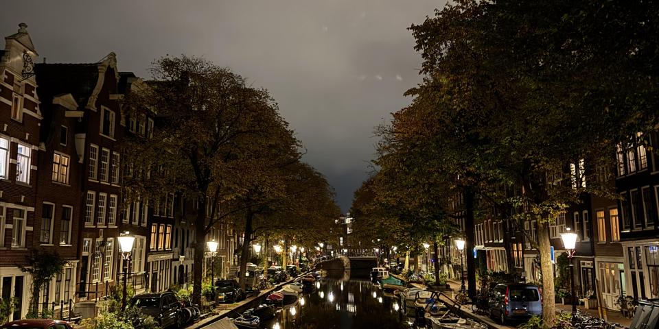 A river with trees and sidewalk to its sides at night