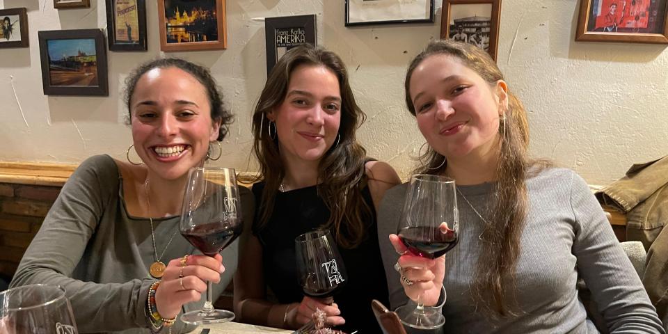 3 female students facing with camera with red wine glasses